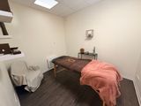 une photo d'une salle de massage avec une table et un fauteuil