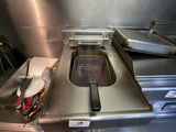 stainless steel counter top in a restaurant kitchen with a fryer and pans on it