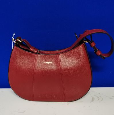 un sac à main en cuir rouge muni d'une poignée en métal, posé sur une table blanche