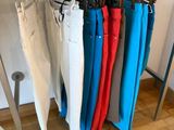 several pairs of pants hanging on a rack in a clothing store