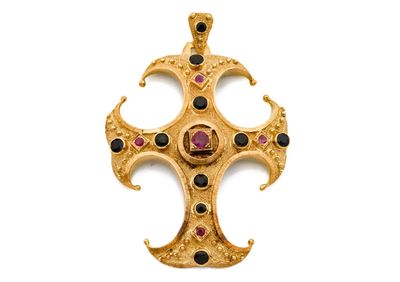 a close up of a gold cross with black and red stones