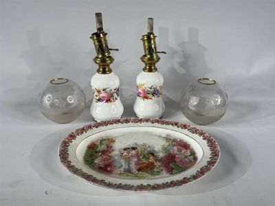 une assiette blanche ornée de fleurs, à côté de deux lampes à huile et d'une assiette décorée d'un motif floral