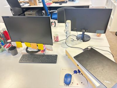 un bureau équipé de deux écrans, d'un clavier, d'une souris et d'un téléphone portable