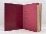 an open book with a red cover sitting on top of a white surface