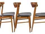 four wooden chairs with black leather seats are lined up against a white background