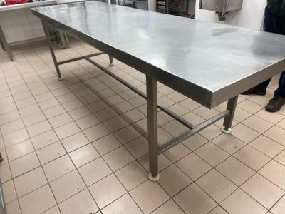 a large stainless steel table in the middle of a kitchen