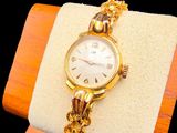 a gold watch on a wooden stand with a chain around it