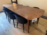 a wooden table with black chairs and a mirror on the wall