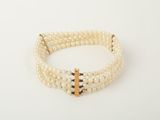 a close up of a bracelet with pearls and a cross on it