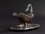 an antique silver plate with a bird on it on a black background