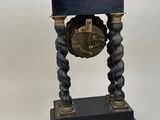 a black clock on a stand on a white background