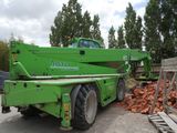 a green crane that is sitting on the back of a truck