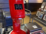 une machine rouge posée sur une table, à côté d'une balance