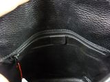 a person holding a black purse with a tag