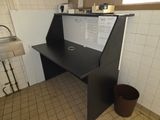a black desk in the corner of a kitchen