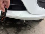 someone is measuring the front bumper of a car with a measuring tape