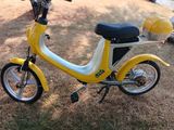 a small yellow and white scooter parked in the grass