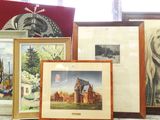 de nombreux tableaux encadrés posés sur une table devant une fenêtre