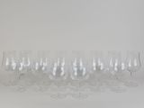 twelve empty wine glasses lined up in a row against a white background