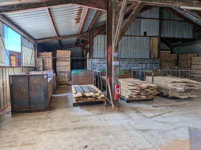 de nombreuses piles de bois dans un entrepôt au toit métallique