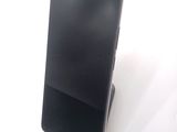 a black cell phone sitting on a stand on a white surface