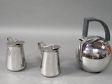 deux pichets en argent et une théière posés sur une table