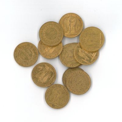 quelques pièces d'or posées sur une surface blanche, sur fond blanc