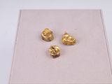 trois pépites d'or dans une boîte posée sur une surface blanche