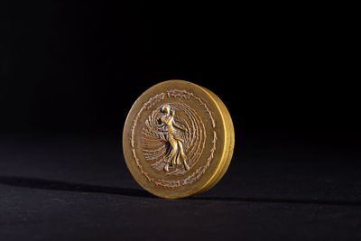 a close up of a gold coin with an image of a woman on it
