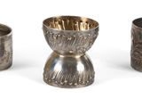 trois vases en argent posés l'un à côté de l'autre sur une surface blanche