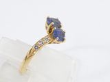 an image of a gold ring with two blue sapphires on top of a clear rock