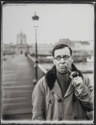 photographie en noir et blanc d'un homme fumant la pipe sur une jetée