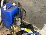 un tas de vieilleries par terre, à côté d'un conteneur bleu