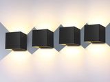 trois lampes cubiques noires fixées au mur, à côté d'un mur blanc