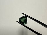 a close up of a pair of tongs holding a green tourmaline stone