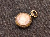une petite montre de poche en or ornée d'une pierre rose