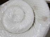 a roll of white yarn wrapped in plastic on a table