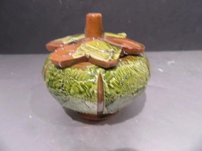 a green vase with a flower on it on a table