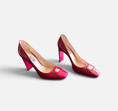une paire de chaussures à talons hauts rouges posées sur une surface blanche