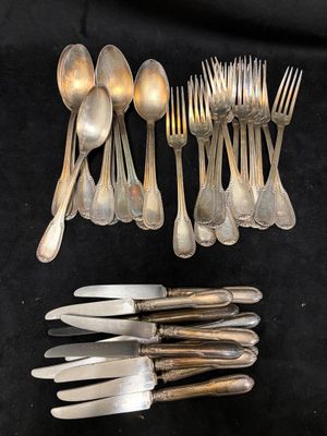 de nombreuses cuillères et fourchettes en argent posées sur une table noire