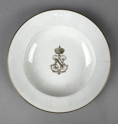 une image représentant une assiette blanche à bord doré, sur laquelle figure une couronne