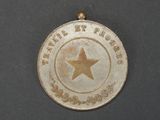 a silver medal with a star on it on a black surface
