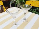 two martini glasses sitting on a table with a yellow chair