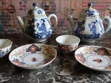 four teapots and two cups sitting on a table