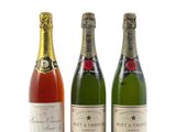 trois bouteilles de champagne sont alignées sur une surface blanche