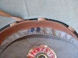 a brown hat with a red and gold badge on it