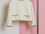 a white jacket hanging on a clothes rack in front of a pink wall