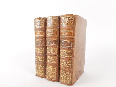 three old books sitting on top of each other on a white surface