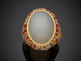 un gros plan d'une bague ornée d'une pierre blanche entourée de pierres multicolores