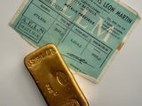 a gold bar next to a boarding card on a table